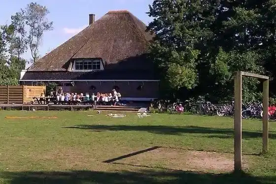 Hoeve Vredestijn vanaf buiten met groep mensen aan tafel